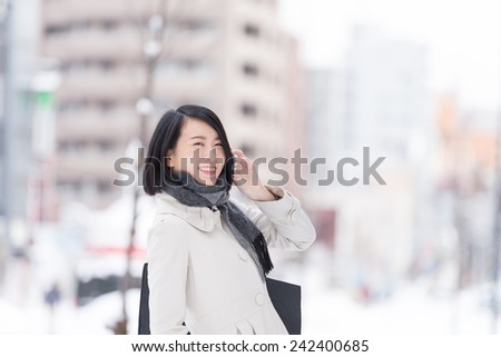 Young Asian woman talking with smart phone on a winter city.