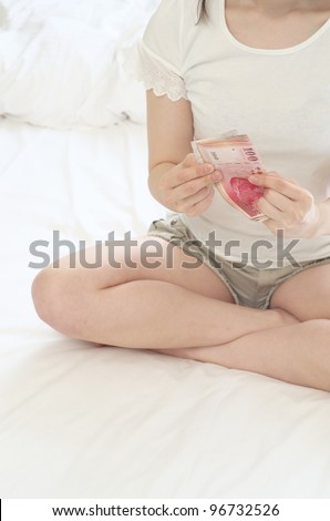Counting New Taiwan Dollars on the bed