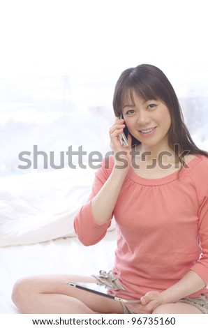 Young Asian woman using a Tablet PC and smart phone on the bed