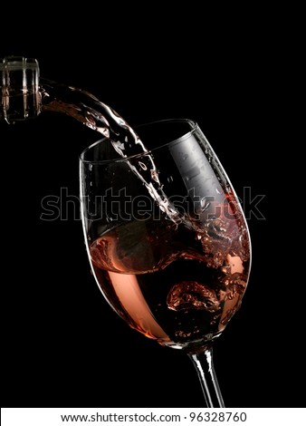 Rose wine pouring in a glass on black background