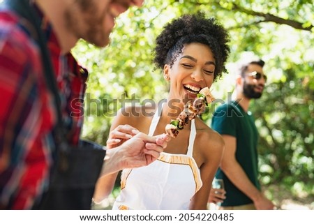 Group of young people having fun in the park at barbecue grilling and eating meat skewers together Foto stock © 