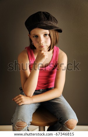 Beautiful young female child wearing a newsboy cap and ripped jeans