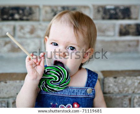 Toddler girl eating a messy lollipop sucker