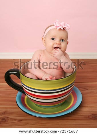 Portrait of cute baby girl sitting inside a giant tea cup or mug