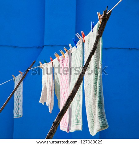 washed laundry hanging on a line to dry with a blue wall in the background, seen in Venice, Italy