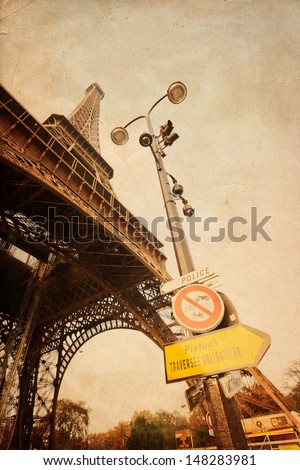 vintage style picture of the Eiffel Tower with a street lamp and traffic signs in the foreground