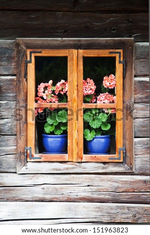 very old and picturesque blockhouse in the Austrian Alps with flowers behind the window