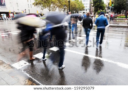 picture of people with umbrellas crossing a street on a rainy day in the city