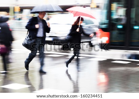 people with umbrellas crossing the wet street
