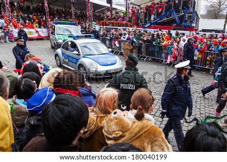 COLOGNE, GERMANY - MARCH 03: unidentified crowd and police escort at the Rose Monday parade on March 03, 2014 in Cologne. The parade is the largest one in Germany.