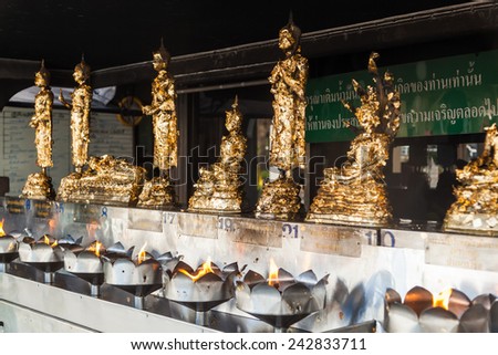 BANGKOK, THAILAND - DECEMBER 10, 2014: golden Buddha sculptures with candles at the Lak Muean Shrine in Bangkok. It is the city pillar shrine of Bangkok