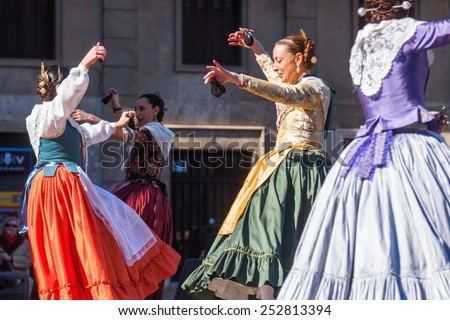 VALENCIA, SPAIN - FEBRUARY 08, 2015: unidentified women in traditional costumes perform a traditional dance on the Plaza de la Virgen in Valencia. Valencia is the 3rd largest city in Spain.