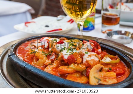 covered Turkish restaurant table with a shrimp casserole and a beer