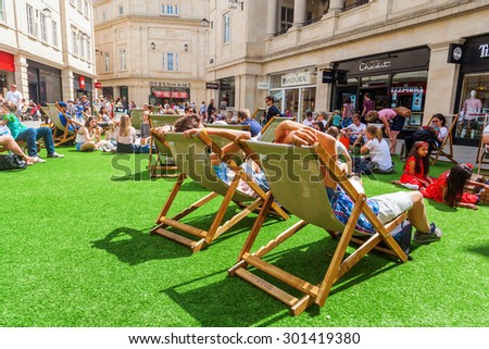 BATH, ENGLAND - JUNE 28, 2015: people on deckchairs in the pedestrian area of Bath with unidentified people. Bath is known for curative Roman-built baths and is a UNESCO world heritage site since 1987