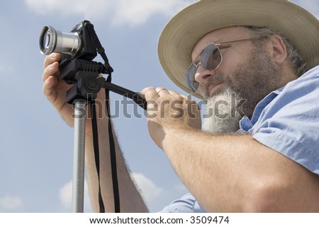 Photograph of a middle aged photographer with a compact camera on a tripod.