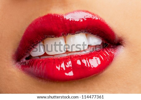 Close-up shot of woman lips wearing red shiny lipstick