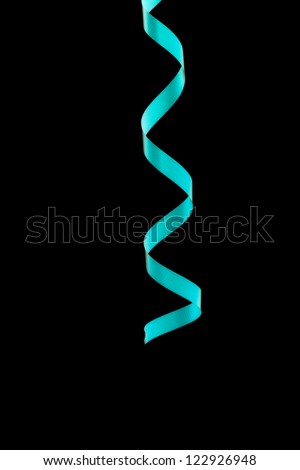 Close-up of curled up party ribbon isolated over black background