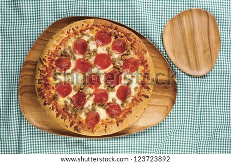 Pizza on wooden pizza pan in a top view image