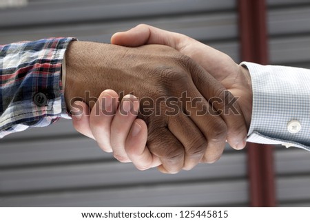Closed up image of black and white hands doing a handshake