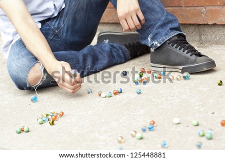 Close-up image of boy\'s hand playing marbles on the street
