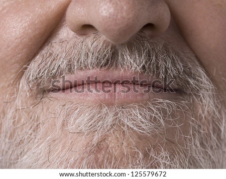 Macro image of an old man face with the camera focused on his bearded mouth