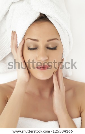 Closed up image of a woman in towel relaxing herself as she touches her face