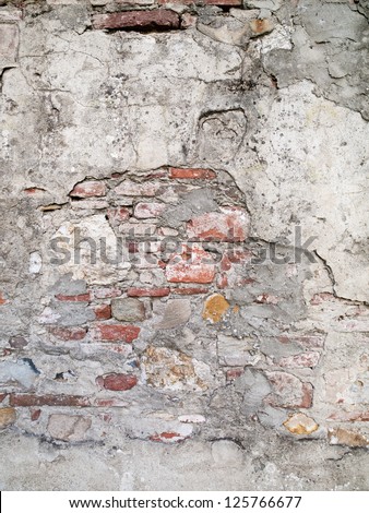Cement plastering with red brick showing through this ancient wall.