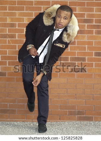 Shot of a man wearing a jacket while leaning on a wall.