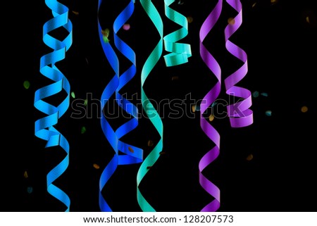 Detail of colorful party streamers and falling confetti over black background