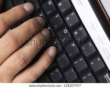 Detailed shot of human fingers touching black computer keyboard.