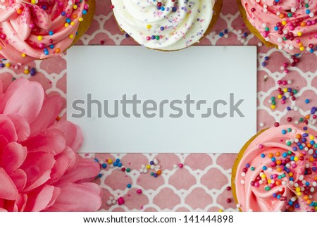 Cropped top view of empty placard with cupcakes and flower.