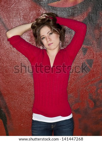 Teenage girl with hands in hair by painted wall.