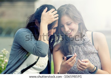 Two Girls While Speaking Looking the cell phone