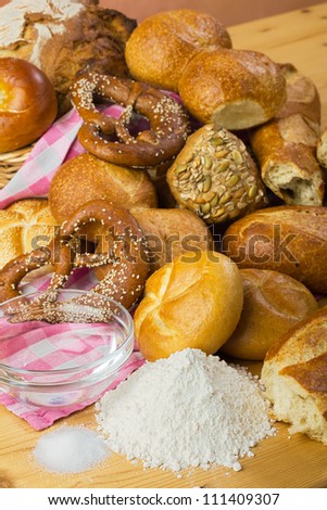 Baking bread with flour, water and salt - rolls, pretzels, white bread, arranged in a group, food still life in warm colors with ingredients