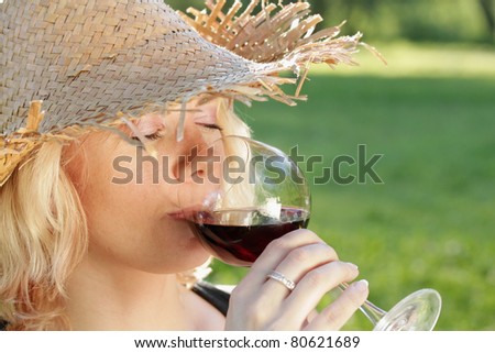 Young woman drinking red wine, outdoor portrait.