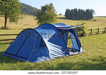 Blue tent campsites planted amidst the mountain meadow Green