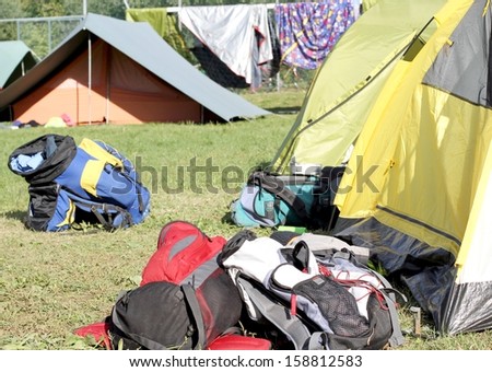 many backpacks of hikers in the midst of camping tents