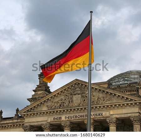 Reichstag building is Parliament of Germany in Berlin with flag. The text  over the main entrance DEM DEUTSCHEN VOLKE meaning To the German People Foto d'archivio © 