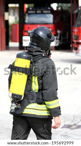 firefighter with yellow  oxygen cylinder and the helmet walks towards the fire