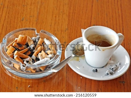 ashtray chock full of cigarette butts and a cup of coffee