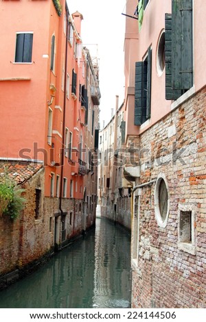 very narrow navigable canal between the tall houses of Venice in Italy