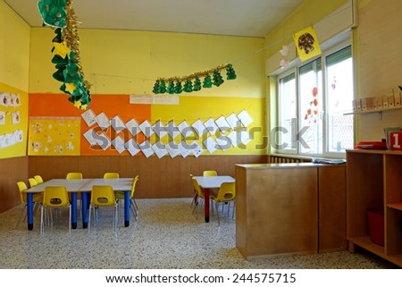 Preschool classroom with yellow chairs and table with drawings of children hanging on the walls