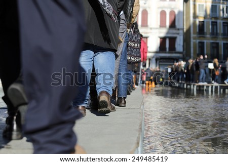 People walking Â onÂ catwalk in Venice Italy during at high tide