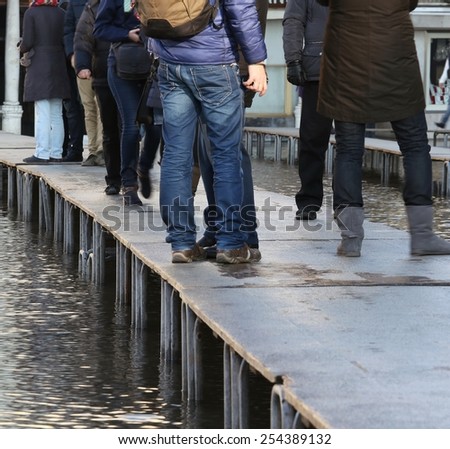 People walking on the elevated walkway in Venice at high tide