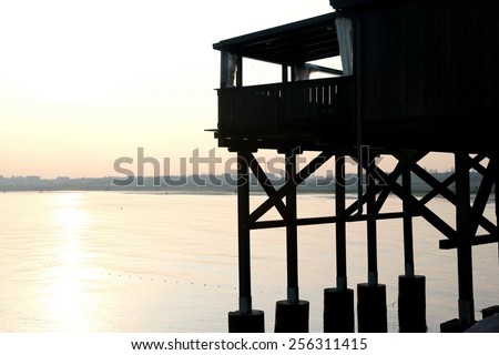 large wooden stilt house on the seashore at sunset