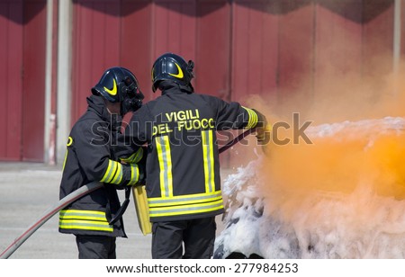 two firefighters in action with foam to put out the fire of the car