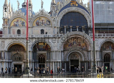 VENICE, VE, ITALY - January 31, 2015: Saint Mark\'s Basilica during high tide  with tourists over the elevated catwalk