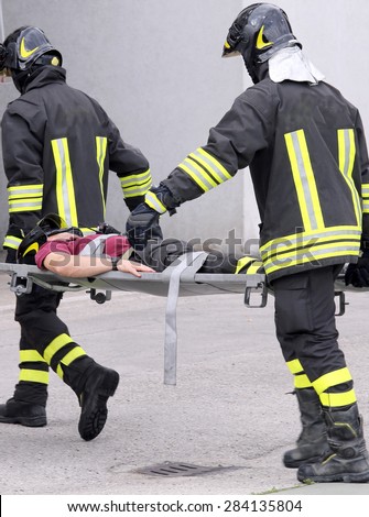 wounded person carried by two firefighters on a stretcher during training in the firehouse