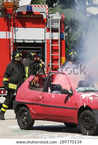 firefighters in action during a road accident with car fire