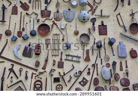 many ancient farming tools hanging on the wall of the rural House